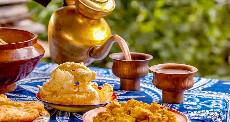 Traditionelle bhutanische Speisen und Getränke, die auf einer dekorativen Tischdecke serviert werden.