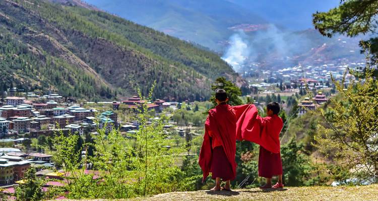 Zwei junge Mönche blicken über ein Tal mit Blick auf die Berge.