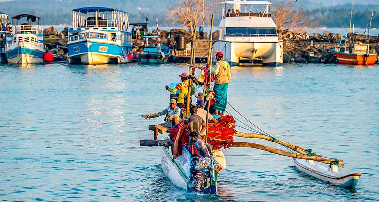 Eine Gruppe von Menschen auf einem Boot in einem Hafen mit Yachten und Fischerbooten.