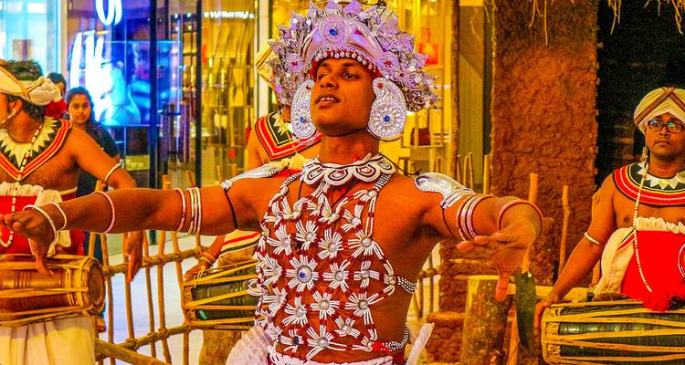 Ein traditioneller Tänzer mit ornamentalen Accessoires und Kopfschmuck, der drinnen auftritt.