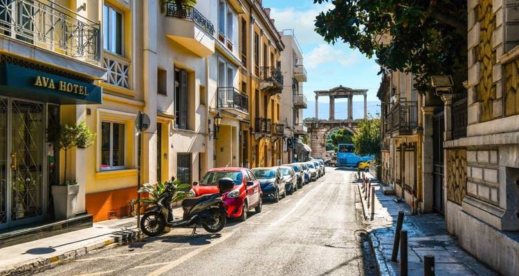 Ruhige Straße im Plaka-Viertel von Athen mit geparkten Autos und Blick auf die Säulen des Tempels des Olympischen Zeus.