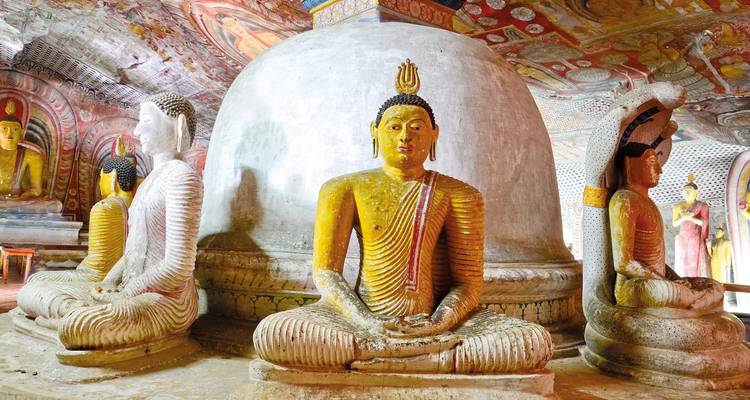 Een tempelinterieur met Boeddhabeelden en een stoepa.