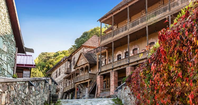 Steingebäude an einer schmalen Straße mit buntem Laub.