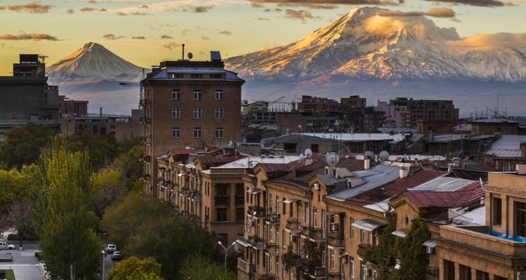 Stadtlandschaft mit Bergen im Hintergrund während des Sonnenuntergangs.