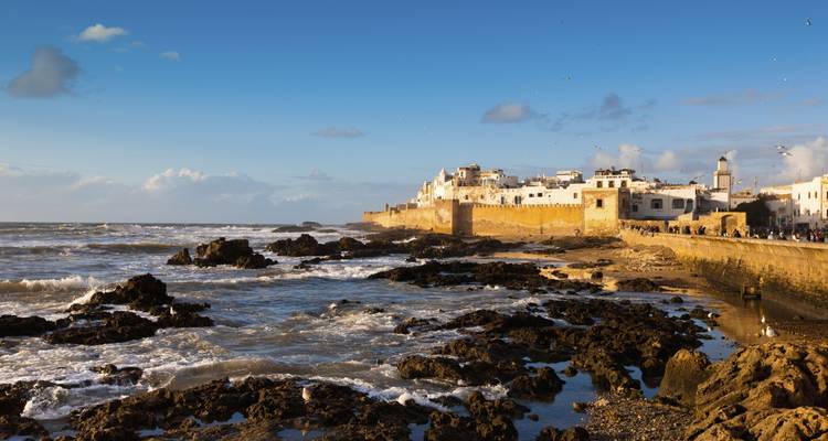 Ommuurde stad aan zee met golven die tegen de rotsen beuken.