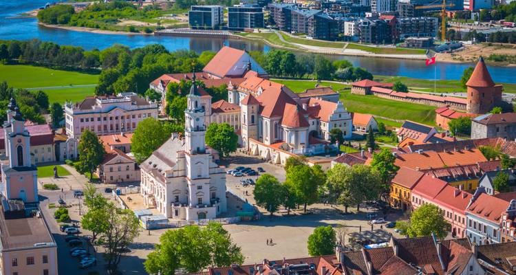 Panoramic aerial of Kaunas Old Town with white Town Hall and red-roofed buildings beside a river bend.