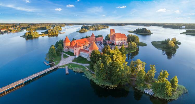 Drone view of Trakai Island Castle surrounded by blue lakes and lush green islets.