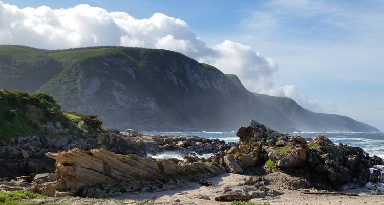 Paysage côtier accidenté avec des vagues qui se brisent contre les rochers.
