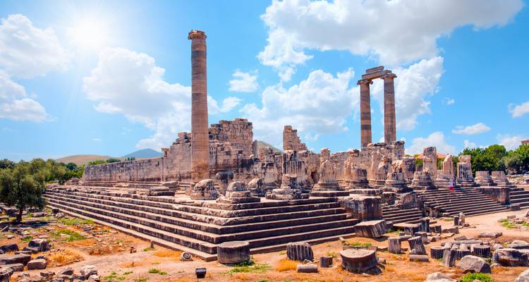 Ruins of an ancient Greco-Roman temple with towering columns under a bright blue sky
