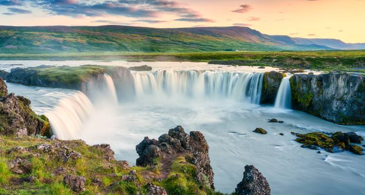 Der mächtige Godafoss-Wasserfall stürzt unter farbenfrohen Abendhimmeln in eine breite Flussschlucht.