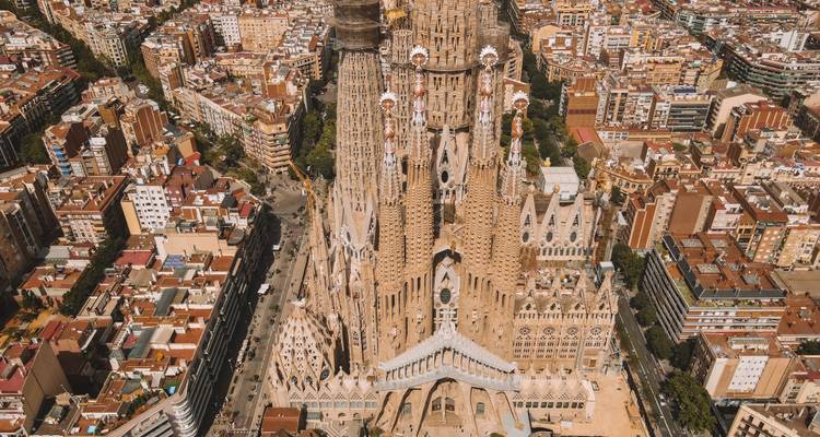 Aerial view of La Sagrada Familia towering over the dense cityscape of Barcelona.