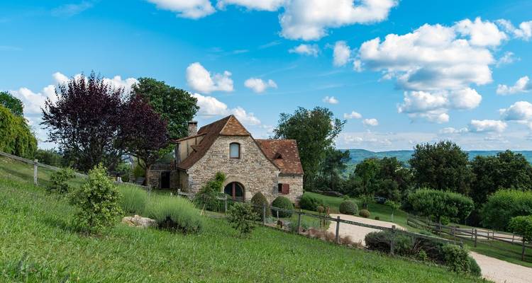Stone house in a rural landscape with lush greenery.