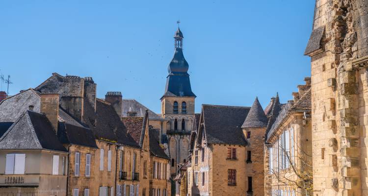 Charmante mittelalterliche Steingebäude und Kirchturm mit Glockenturm unter einem klaren blauen Himmel in einer kleinen Stadt.