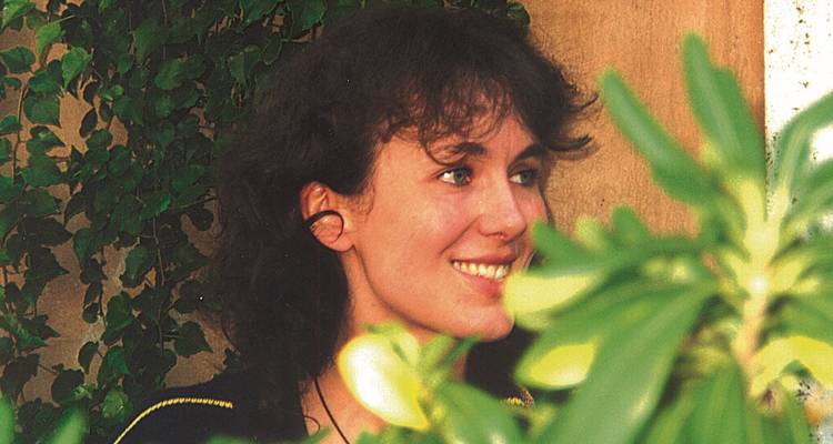 Porträt einer lächelnden Person, umgeben von Grün