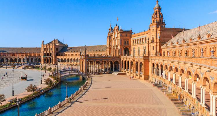 Ikonischer Plaza de España in Sevilla mit beeindruckendem halbkreisförmigen Gebäude, Kanal und klarem blauem Himmel.