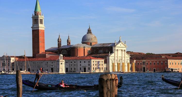 Gondolas on a canal with historic buildings in the background.