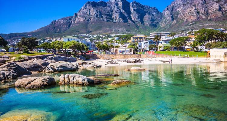 Crystal clear beach with turquoise waters and mountains in the background.