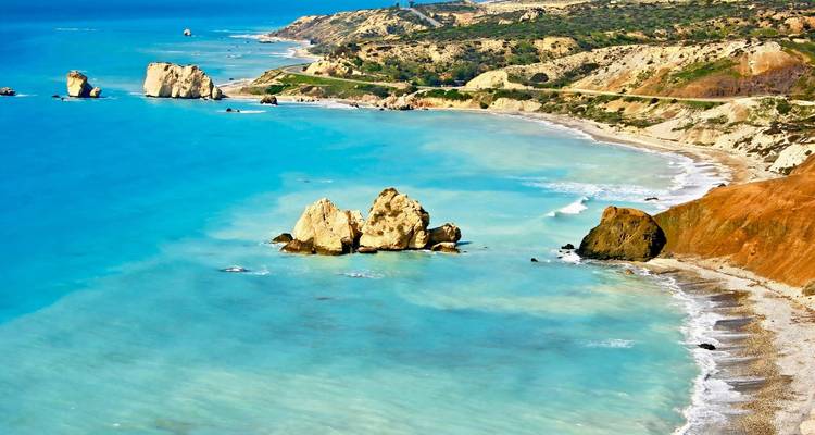Sonniger Strand mit felsiger Landschaft und türkisfarbenem Wasser.