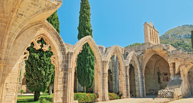 Gotische Bögen in einer sonnigen Gartenlandschaft.