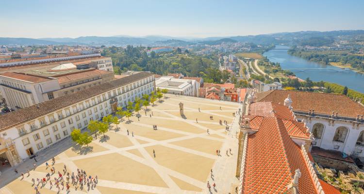 Vue panoramique sur la cour historique de l'Université de Coimbra avec le fleuve et les collines en arrière-plan.