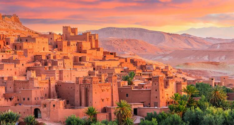 Traditional clay buildings on a hill at sunset.