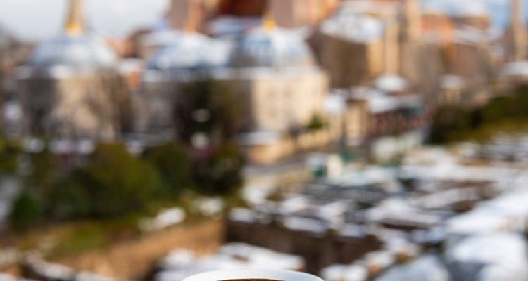 Eine verschwommene Ansicht einer Stadtlandschaft mit einer Kaffeetasse im Fokus.