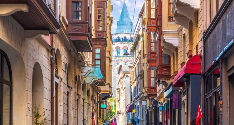Eine lebendige Straße mit historischen Gebäuden und einem Turm in der Ferne.