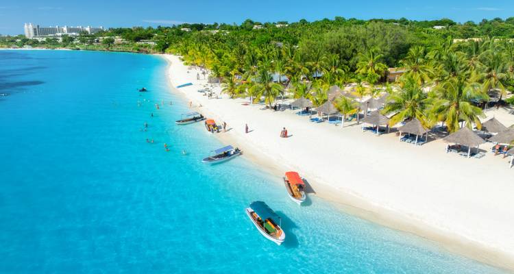 Menschen, die einen weißen Sandstrand mit türkisfarbenem Wasser und Palmen genießen.