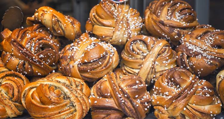 Nahaufnahme von schwedischen Zimtschnecken mit Perlzucker bestreut in einem Bäckereifenster.