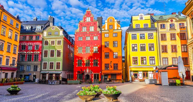 Lebhaft bemalte mittelalterliche Stadthäuser des Stortorget-Platzes unter einem strahlend blauen Himmel.