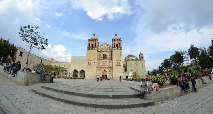 Eine historische Kirche mit einem großen Platz und Menschen, die sich unterhalten.