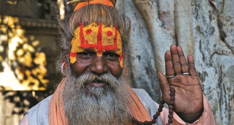 Porträt eines lächelnden Mannes mit leuchtenden gemalten Mustern im Gesicht.