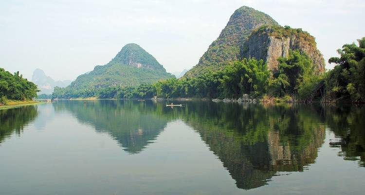 Montagnes karstiques reflétées dans une rivière calme.