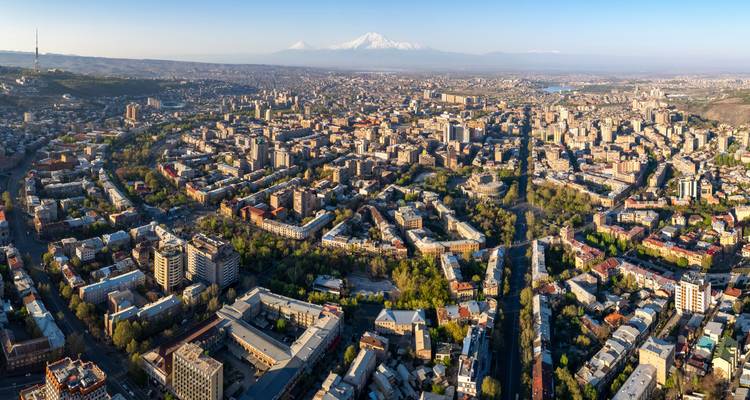 Luftpanorama der Stadt Eriwan mit dem schneebedeckten Berg Ararat in der Ferne unter klarem Morgenlicht.