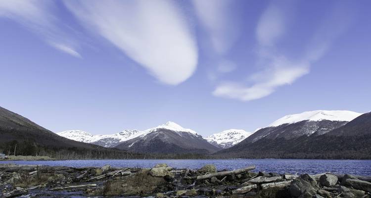Snow-capped mountains and a lake under an expansive sky.