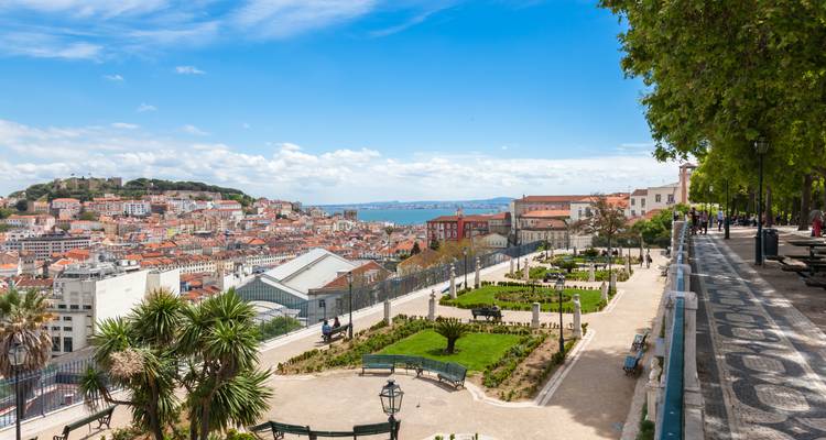 Ein Panoramablick-Garten mit Aussicht auf Lissabons terrakottafarbene Dächer, den Fluss Tagus und entfernte Hügel an einem sonnigen Tag.