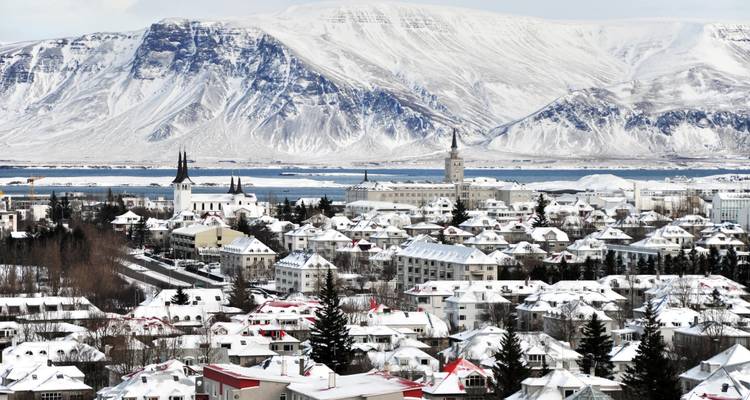 Schneebedeckte Reykjaviker Stadtlandschaft mit Bergen auf der anderen Seite der Bucht.