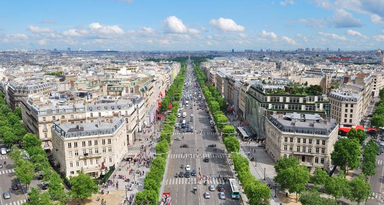 Langer Blick die Champs-Élysées hinunter, gesäumt von Bäumen und voller Verkehr und Fußgänger.