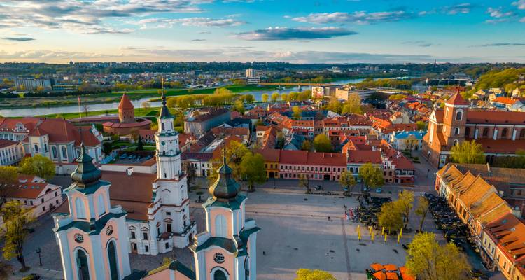 Farbenfrohe Luftaufnahme des Altstadtplatzes von Kaunas, der Kirchen und des mäandernden Flusses Nemunas im Licht der untergehenden Sonne