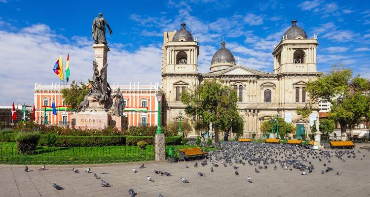Stadtplatz mit einer Statue und einer Kathedrale mit Tauben.