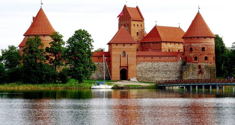 Grand château médiéval sur un lac avec des murs en briques rouges.