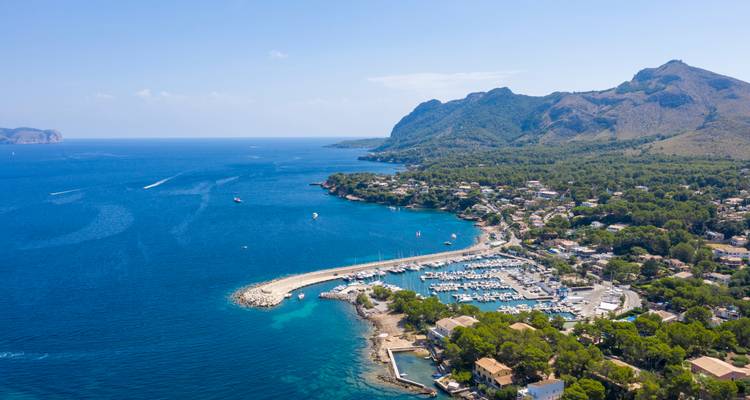 Vista aérea de un puerto deportivo y un pueblo costero rodeados de aguas azul profundo del Mediterráneo