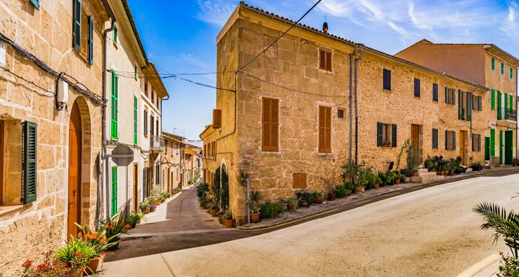 Encantadora calle estrecha del pueblo bordeada de casas de piedra y persianas verdes