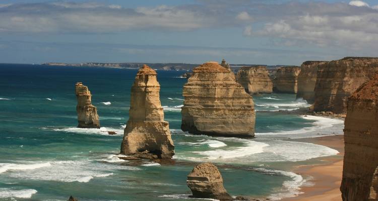 View of the Twelve Apostles rock formations along the coast with ocean waves.