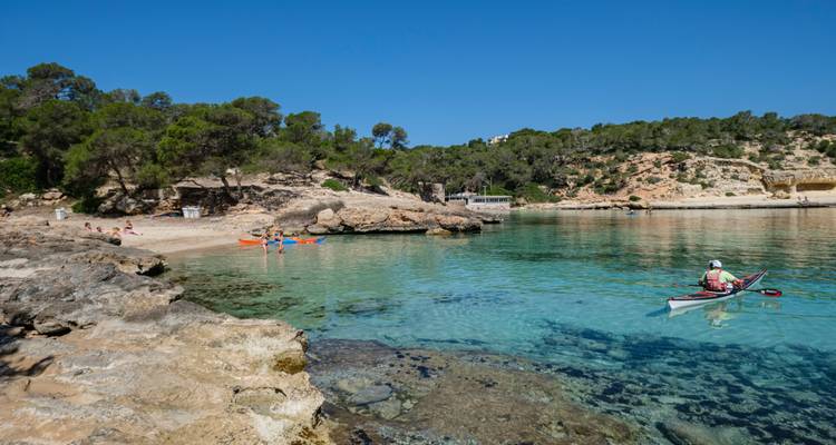 Heldere turquoise baai met kajakvaarders en zonnebaders op een klein zandstrand