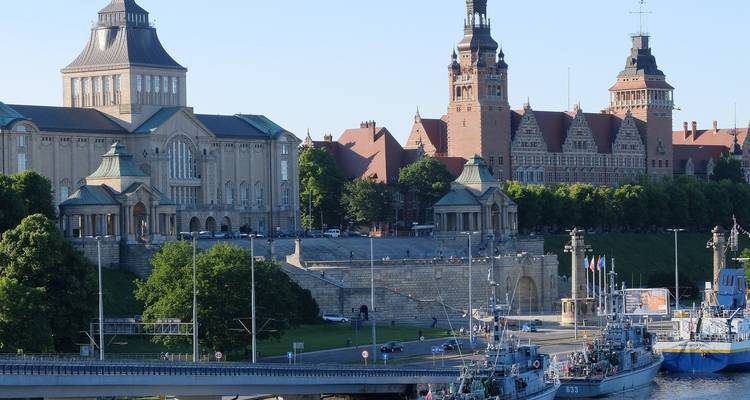 Historisches Flussufer mit Booten und großem Gebäude.