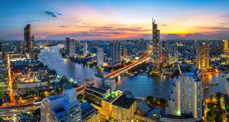 Panoramablick in der Dämmerung auf die Skyline von Bangkok mit dem Chao Phraya Fluss und beleuchteten Brücken.