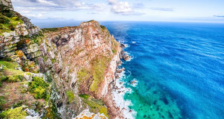 Uitzicht vanaf de klif met helder blauw water en ruige rotsformaties.