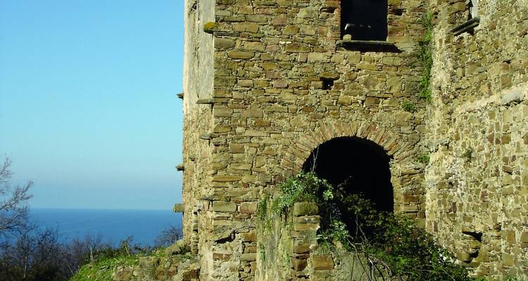 Old stone building ruins with a view of the sea in the background.