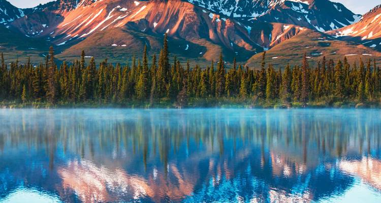 Berglandschaft mit einem See, der die Berge und Bäume widerspiegelt.
